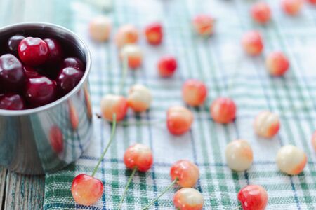 Cherries in a steel mug on a fabric background.