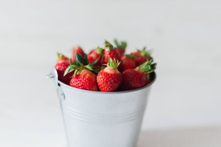 Juicy fresh strawberries in a metal bucket on a white background.の写真素材