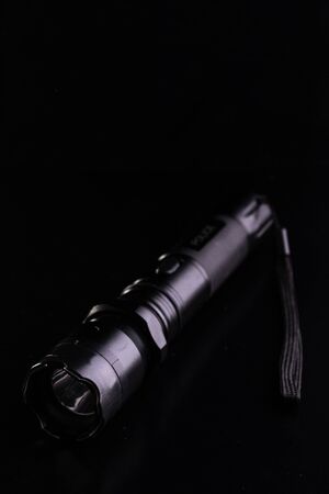 Black tactical flashlight on a black background.の写真素材