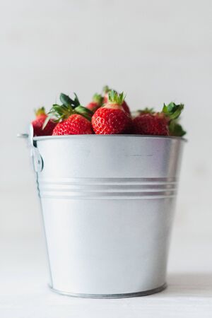 Juicy fresh strawberries in a metal bucket on a white background.の写真素材