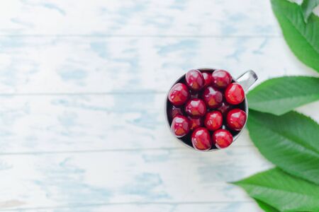 Cherries in a steel mug on a wooden background.の写真素材