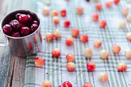 Cherries in a steel mug on a fabric background.の写真素材