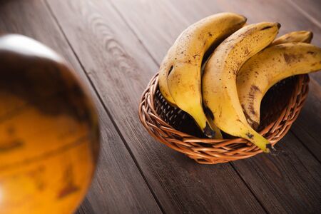 Bananas in a basket on a wooden brown natural background near a brown globe.の写真素材