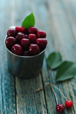 Cherries in a steel mug on a wooden background.の写真素材