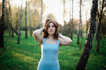 Beautiful young girl in a blue dress in a spring park.の写真素材