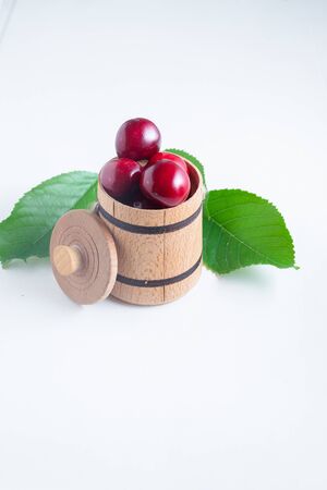 Sweet cherry berries in a wooden small barrel on a white background isolate.の写真素材