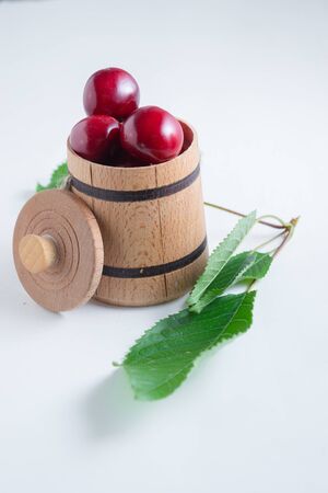 Sweet cherry berries in a wooden small barrel on a white background isolate.の写真素材