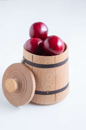 Sweet cherry berries in a wooden small barrel on a white background isolate.の写真素材