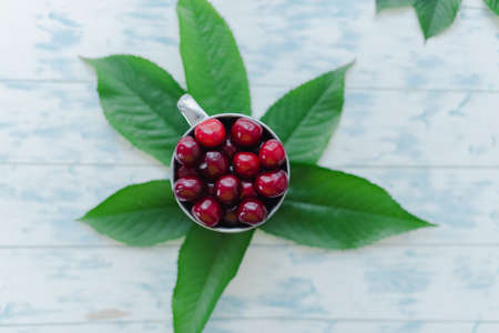Cherries in a steel mug on a wooden background.の写真素材