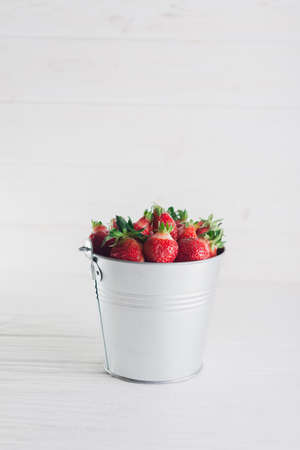 Juicy fresh strawberries in a metal bucket on a white background.の写真素材
