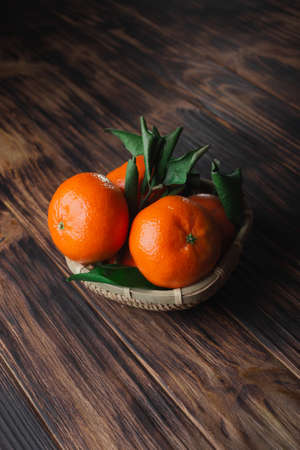 Fresh tangerines with leaves on a wooden old background.