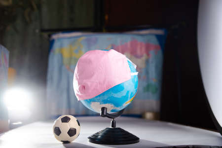 Globe in a medical mask with a soccer ball. The concept of canceling football matches due to coronavirus.の写真素材