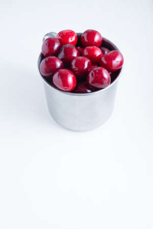Sweet cherries in a steel mug on a white paper background.の写真素材