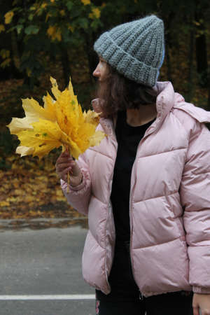 Girl in a warm 2-colored hat, autumn forest with yellow leavesの写真素材