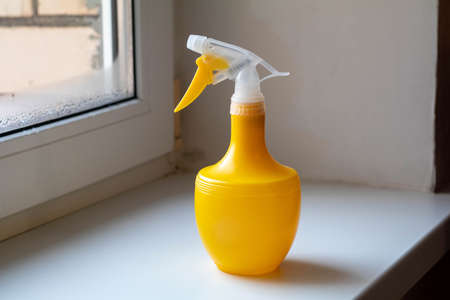 Yellow spray bottle for washing stands on the windowsillの写真素材