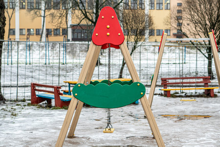 Childrens playground with swings and benches in winter