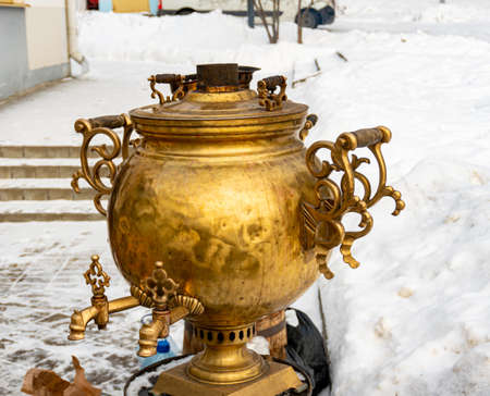 Russian gold samovar with hot drink on the table in winter, luxury teapot, antiquesの写真素材