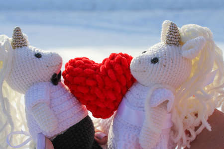 Crochet toys unicorns in wedding suits with a red heart, love storyの写真素材