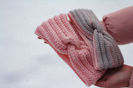 Knitted womens headbands in hands on snow backgroundの写真素材