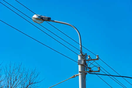 Lamp post with wires on blue sky background, city lightingの写真素材