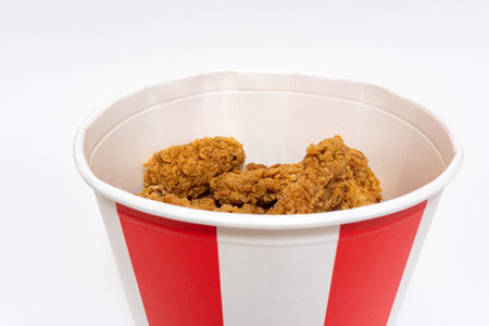 Deep fried spicy chicken wings in a crispy breading in a basket, chicken fast food isolated on white...