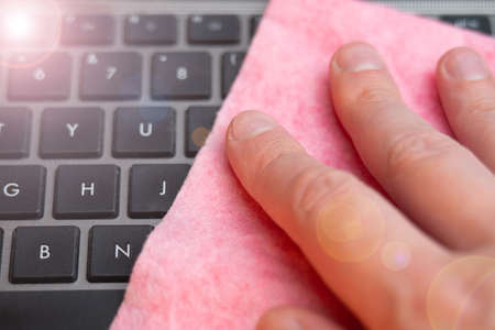 Hand wipes laptop keyboard with a damp microfiber clothの写真素材