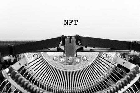 NFT word closeup being typing and centered on a sheet of paper on old vintage typewriter mechanicalの写真素材