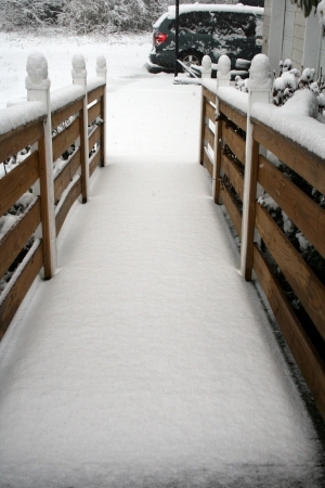 Snow covered handicap ramp and driveway leading to snow covered carの写真素材