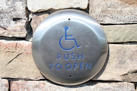 Silver handicap push to open button with wheelchair emblem on silver buttonの写真素材