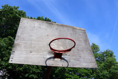Old Basketball Board and Hoop Against the Sky and Green Treeの写真素材