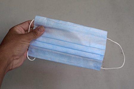 hand holding a surgical face maskÂ 