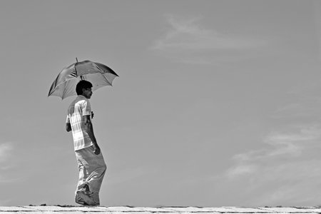 A South Asian Man walking with a umbrella at summer seasonのeditorial素材