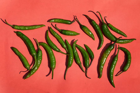 Green Chilli spice vegetables on red background. Pepper for recipe delicious taste. Capsicum...