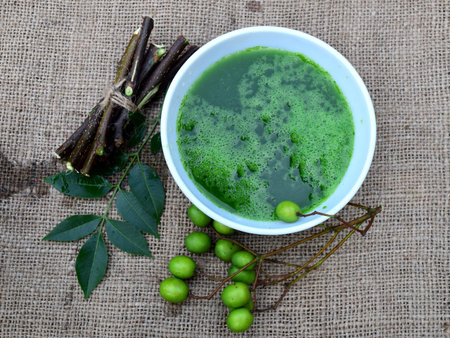 Neem leaves, fruits, and branches on jute fabric background. Neem medicinal herb juice in bowl. Neem...