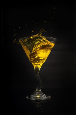 martini drink splash gold isolated on black backgroundの写真素材