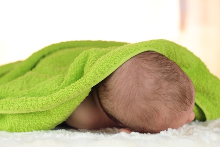 A portrait of cute sleeping baby with a blanket over his head の写真素材