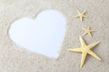 Empty white heart and starfishes on the beachの写真素材