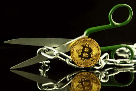Physical version of Bitcoin, scissors and chain. Conceptual image for Blockchain Technology and hard fork (term refers to a situation when a blockchain splits into two separate chains).の写真素材