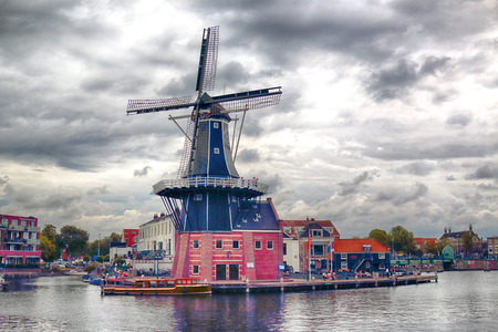 HAARLEM, NETHERLANDS - JULY 09, 2018 : Spaarne river with windmill Adriaan and beautiful clouds. Typical Dutch architecture.のeditorial素材