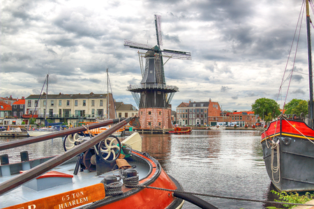HAARLEM, NETHERLANDS - JULY 09, 2018 : Spaarne river with windmill Adriaan and beautiful clouds. Typical Dutch architecture.のeditorial素材