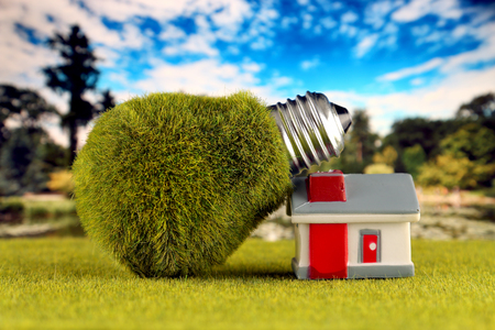 Green eco light bulb and miniature house. Renewable energy concept. Electricity prices, energy saving in the household.の写真素材