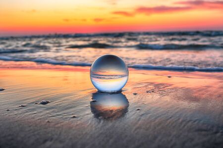 Beautiful sunset on the beach in Slowinski National Park near Leba, Poland. View through a glass, crystal ball (lensball) for refraction photography. Wild, untouched nature.の写真素材