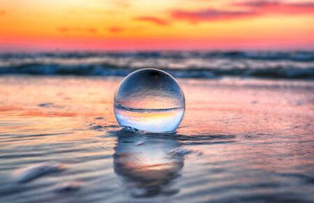 Beautiful sunset on the beach in Slowinski National Park near Leba, Poland. View through a glass, crystal ball (lensball) for refraction photography. Wild, untouched nature.の写真素材