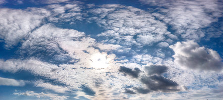 Blue sky with clouds and sun in late September background.