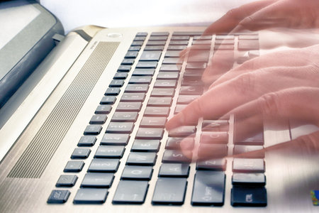 Close-up of a black laptop keyboard with male hands.
