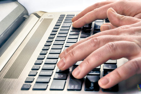 Close-up of a black laptop keyboard with male hands.