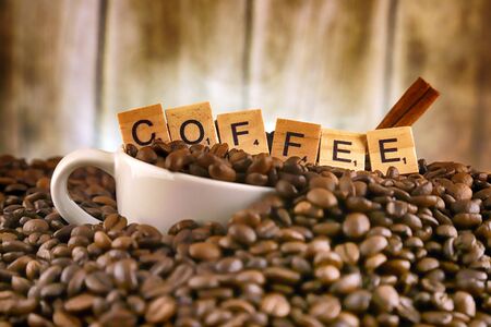 WROCLAW, POLAND - FEBRUARY 05, 2020: White porcelain cup in coffee grains, and word COFFEE made of small wooden letters. Conceptual image for lovers of delicious coffee.のeditorial素材