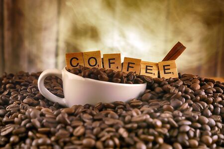 WROCLAW, POLAND - FEBRUARY 05, 2020: White porcelain cup in coffee grains, and word COFFEE made of small wooden letters. Conceptual image for lovers of delicious coffee.のeditorial素材