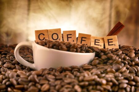 WROCLAW, POLAND - FEBRUARY 05, 2020: White porcelain cup in coffee grains, and word COFFEE made of small wooden letters. Conceptual image for lovers of delicious coffee.のeditorial素材