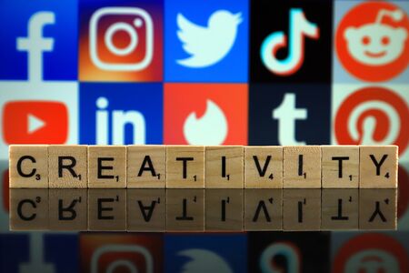 WROCLAW, POLAND - FEBRUARY 12, 2020: Word CREATIVITY made of wooden letters, and FACEBOOK, INSTAGRAM, TWITTER, TIK TOK, REDDIT, YOUTUBE, LINKEDIN, TINDER, TUMBLR, PINTEREST logos in the background.のeditorial素材